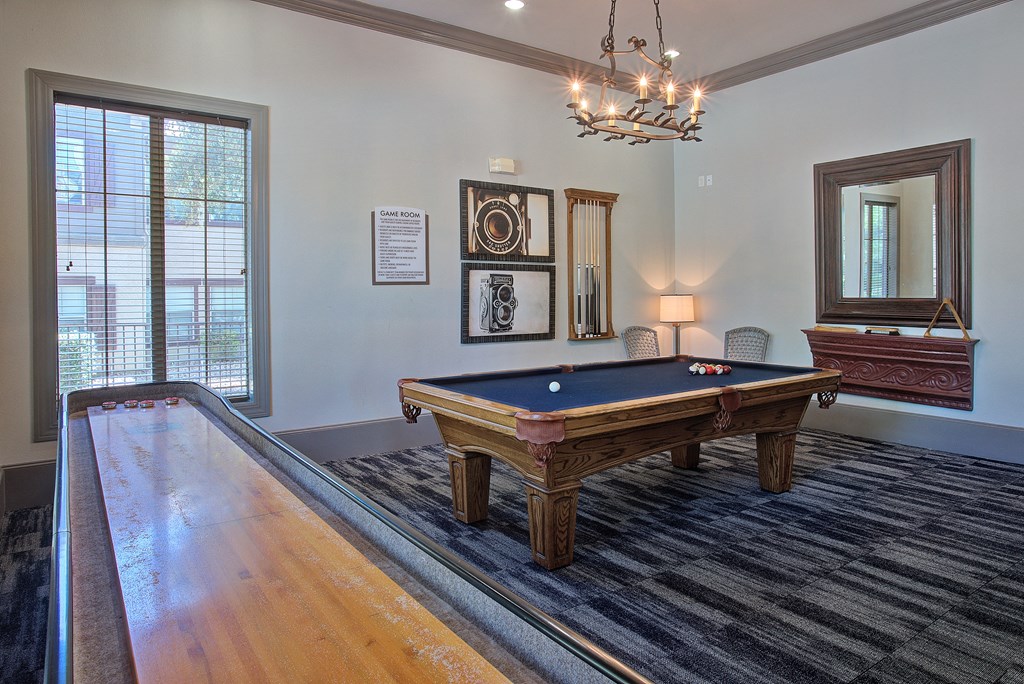 A pool table in a room with a chandelier and a mirror.