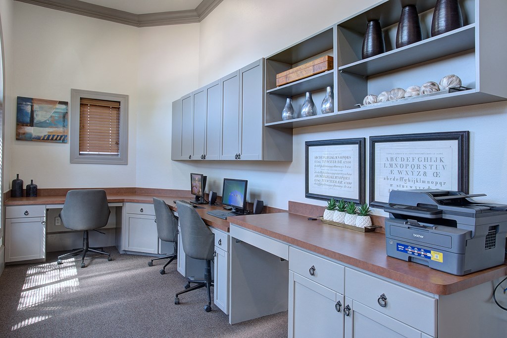 A well-lit office with a desk, chairs, and a printer.
