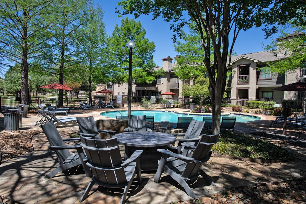 A table and chairs set is in the foreground of a pool area.