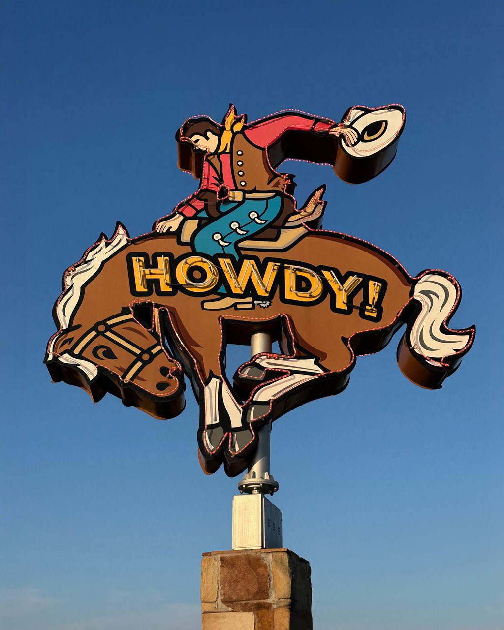 A large sign of a cowboy riding a bucking horse with the word "Howdy!" on it.