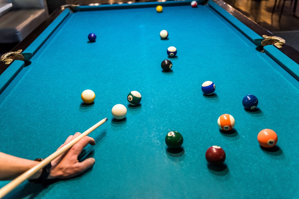 A person is playing pool with a cue in hand.