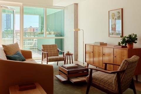 A living room with a chair, a sofa, a table, and a plant.