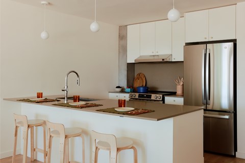 A kitchen with a white counter and wooden chairs.