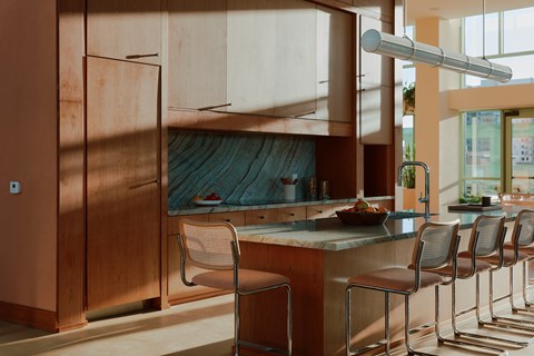 A kitchen with brown cabinets and a counter with chairs.