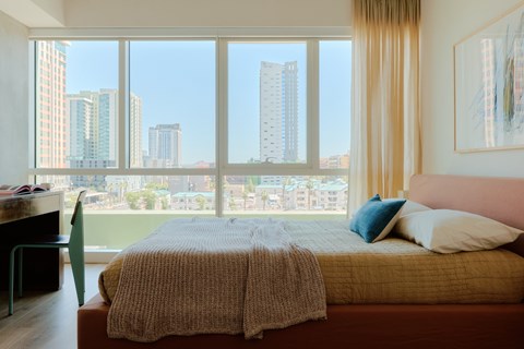 A bedroom with a large bed and a view of the city.