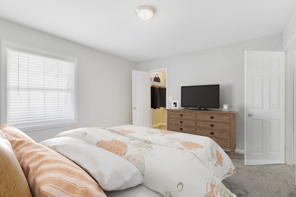 a bedroom with a bed and a dresser with a tv