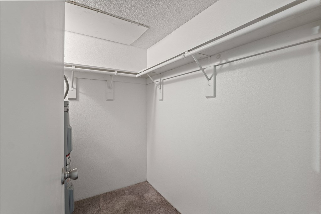 A white wall with a door and a white ceiling with a white pipe.
