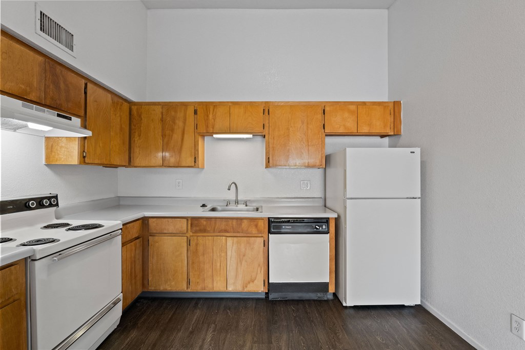 A kitchen with white appliances and wooden cabinets.