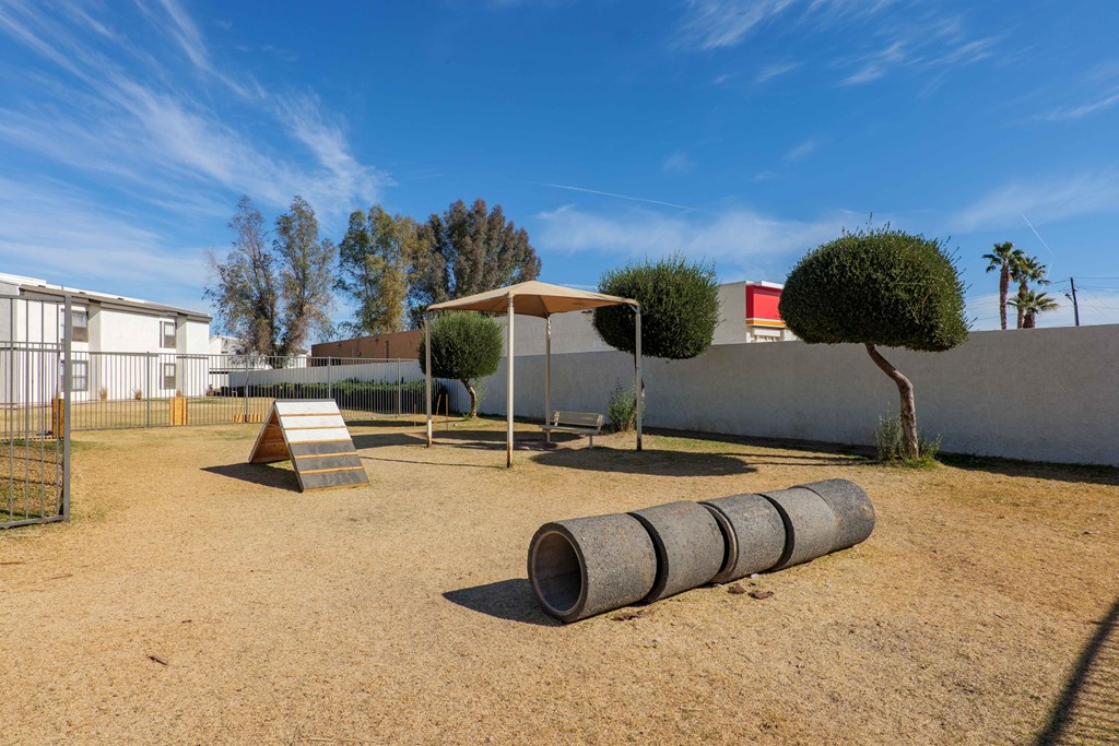 A playground with a slide, swings, and a tree.