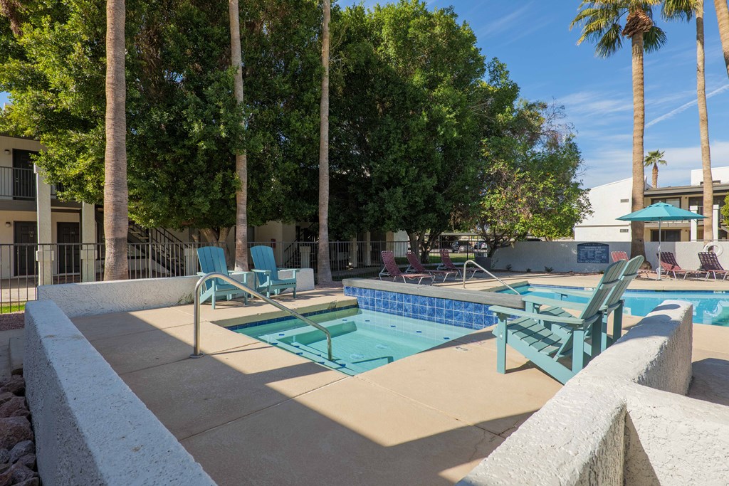 A pool surrounded by trees and chairs.