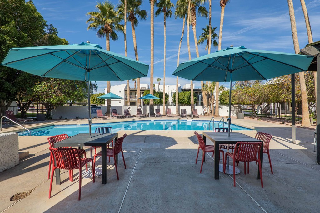 A poolside area with tables and chairs and umbrellas.