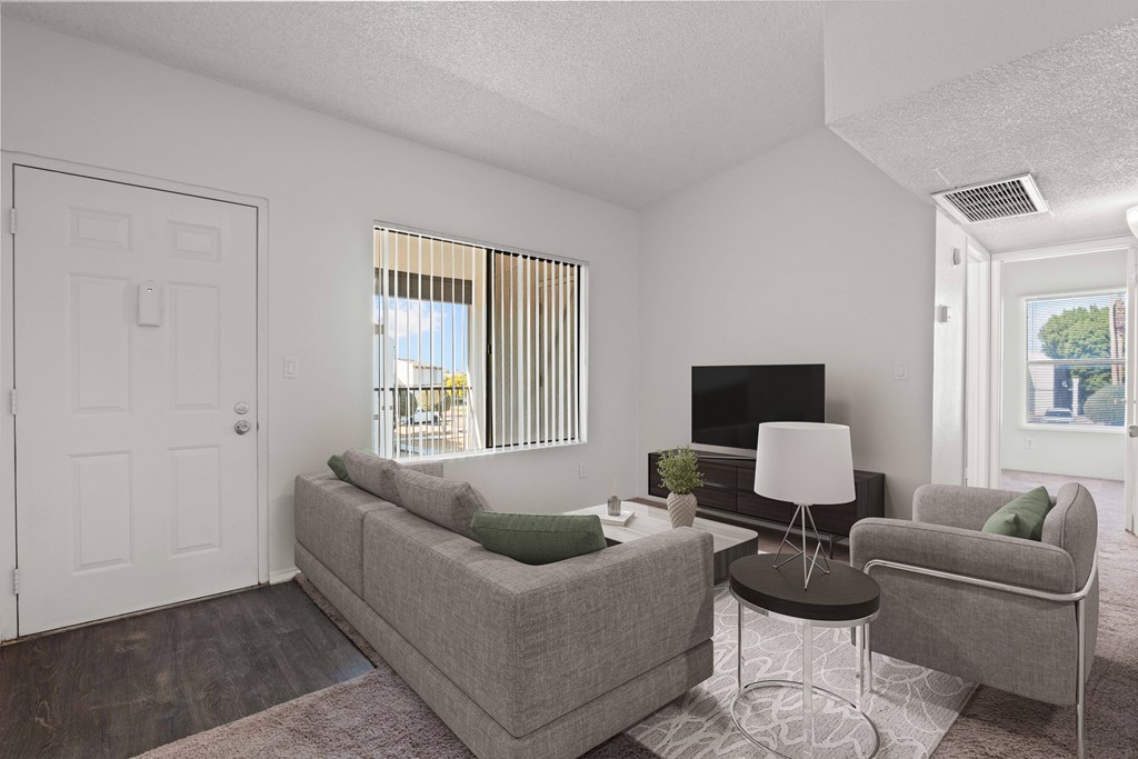 A living room with a grey couch, a white lamp, and a television.