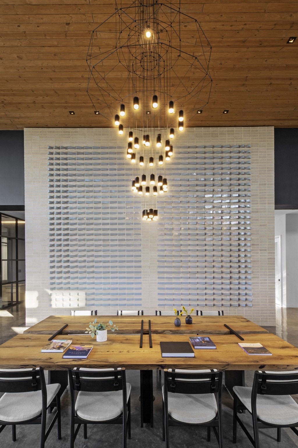 a large wooden table with chairs and a chandelier hanging from the ceiling