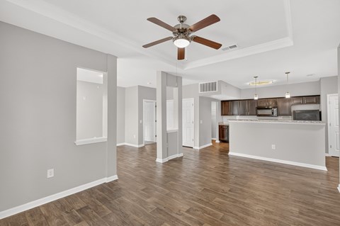 A spacious living room with a ceiling fan and hardwood floors.