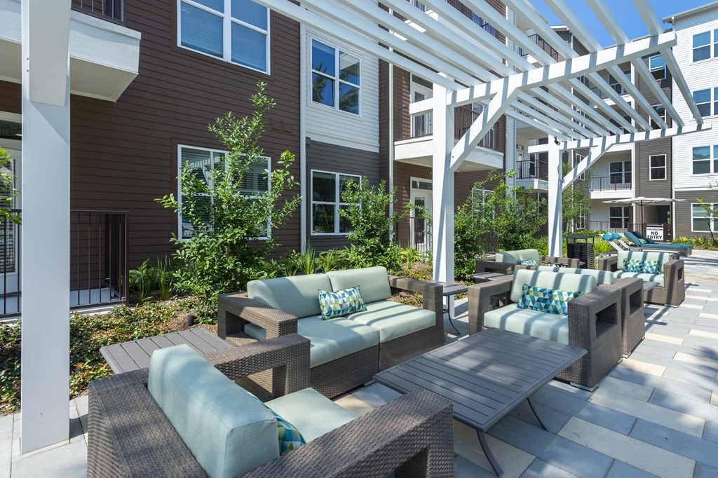 a patio with tables and chairs under a white pergola