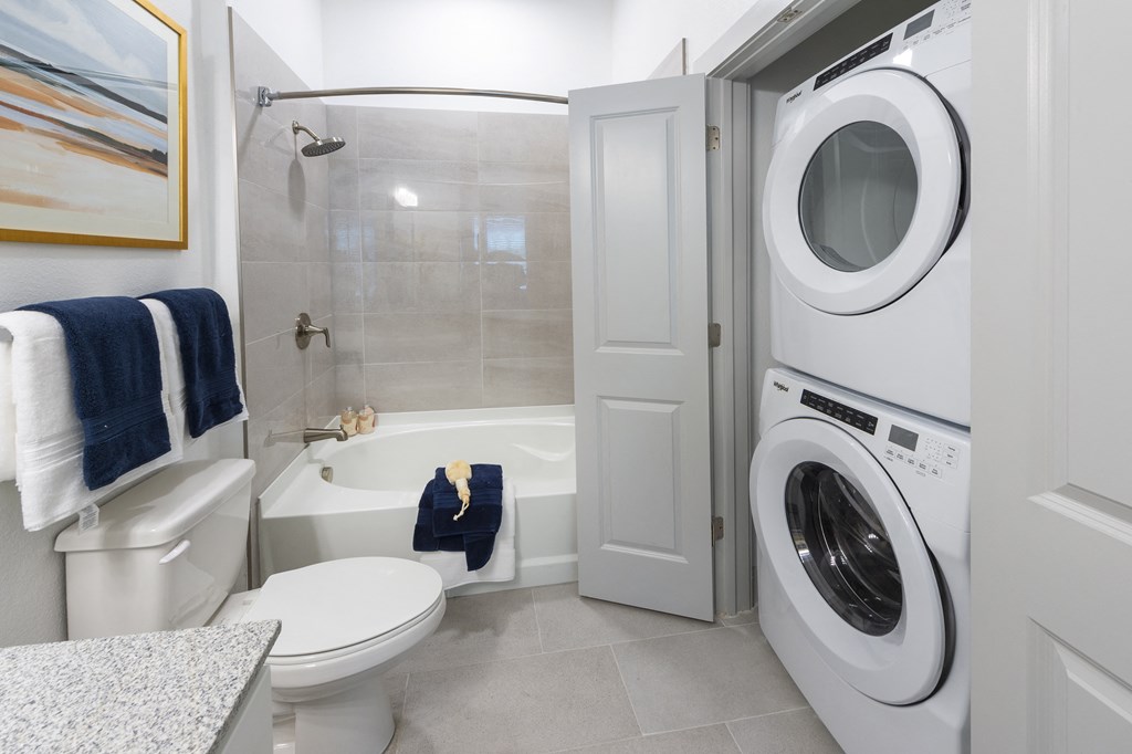 a bathroom with a washer and dryer in it and a toilet and tub