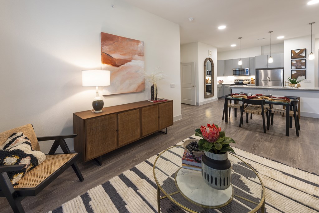 a living room and kitchen with a table and a vase of flowers