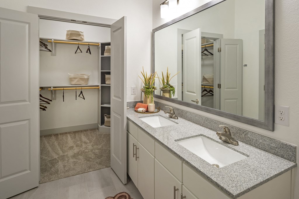 a bathroom with two sinks and a mirror and a closet