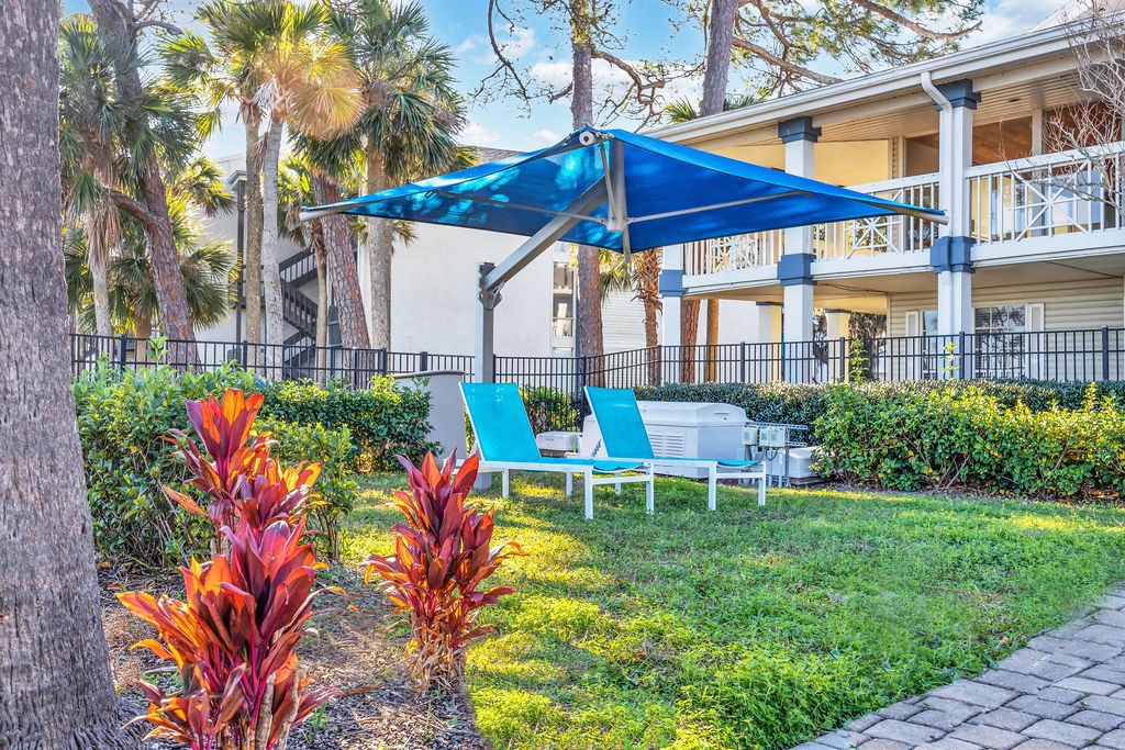 a patio with a blue umbrella and chairs in front of a building