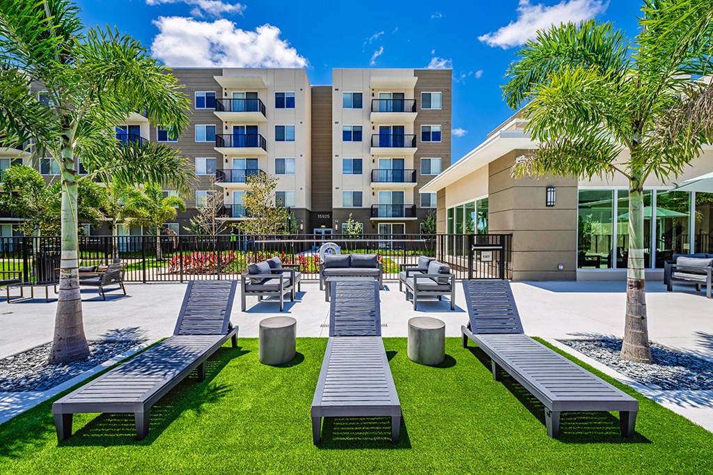 A modern building with a grassy area in front and benches for seating.