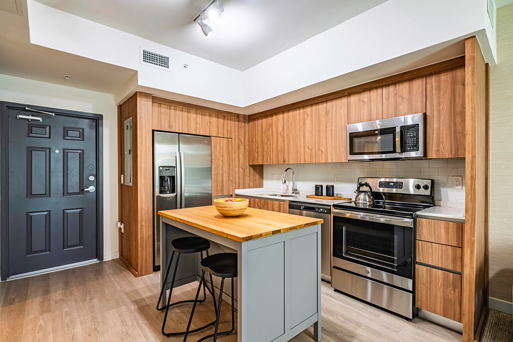 A kitchen with a wooden counter top and stainless steel appliances.