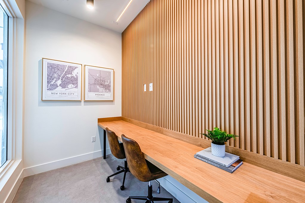 A room with a long wooden desk and two chairs.