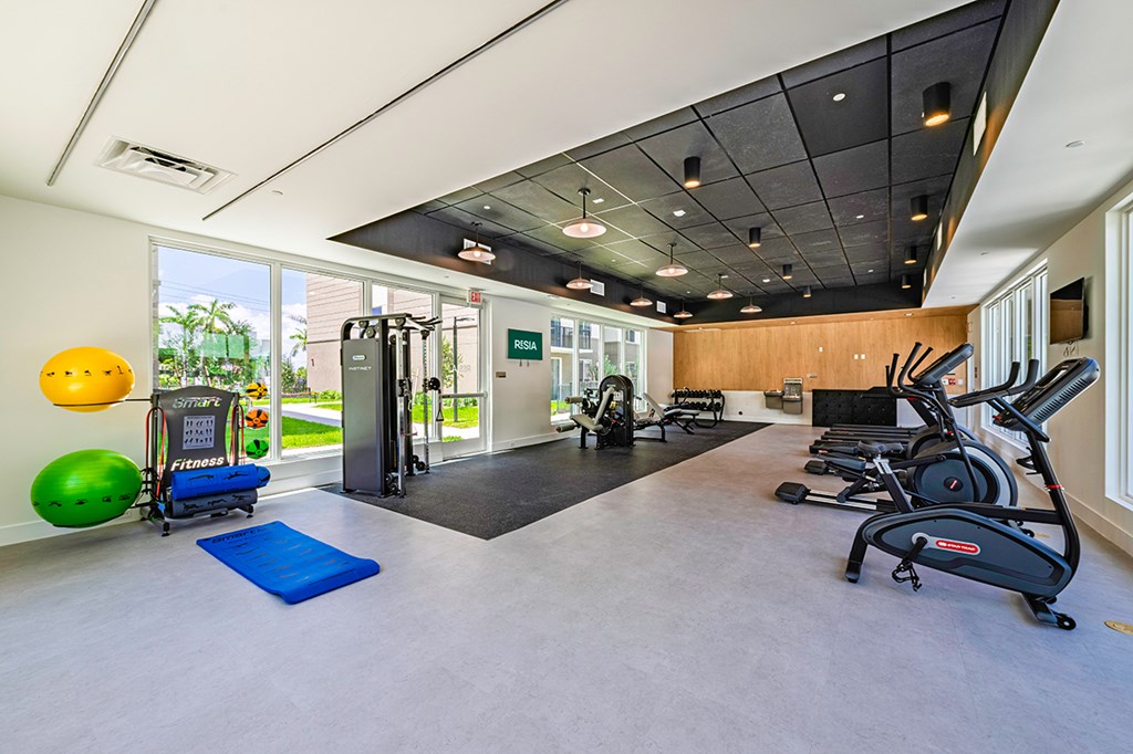 A gym with a variety of equipment including treadmills, exercise balls, and weights.