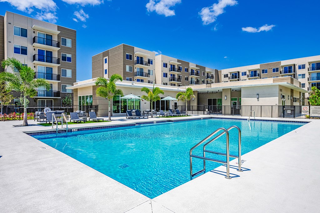 A large swimming pool is surrounded by apartment buildings.