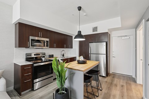 A modern kitchen with dark brown cabinets and stainless steel appliances.
