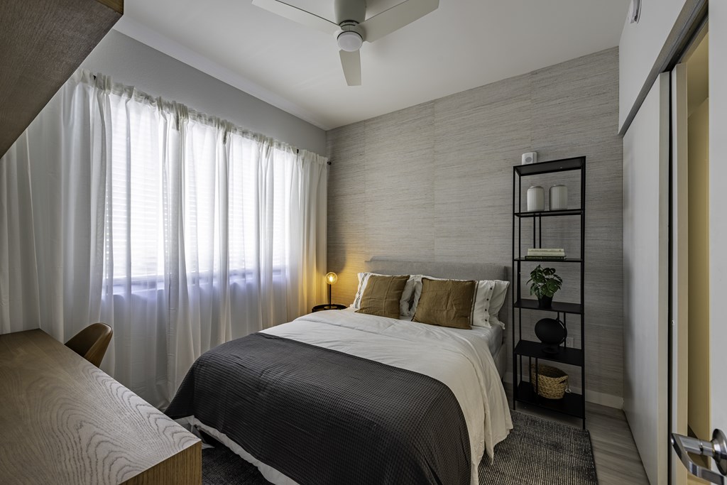 A bedroom with a bed, a table, and a chair.