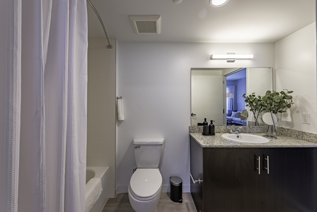 A bathroom with a toilet, sink, and mirror.