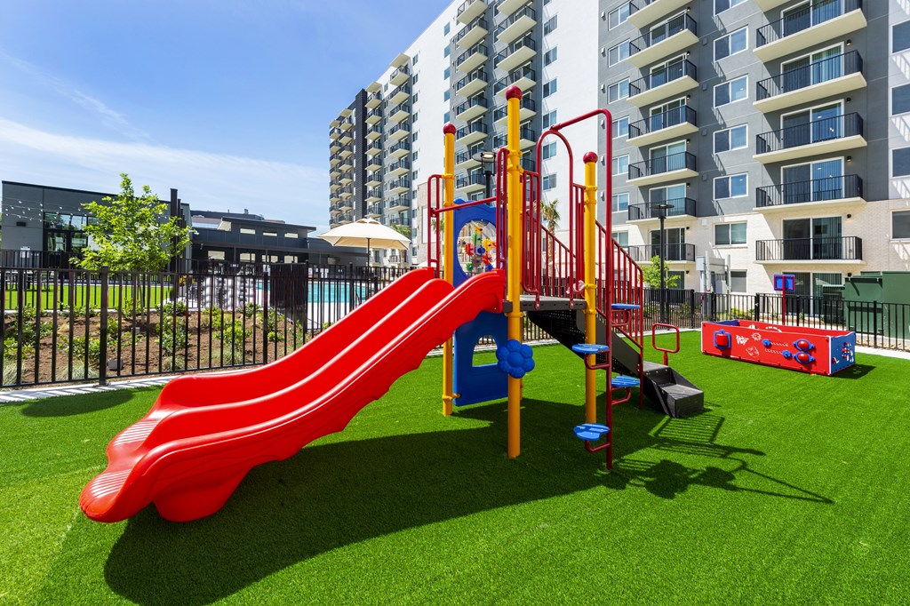 a playground at an apartment building with a red slide