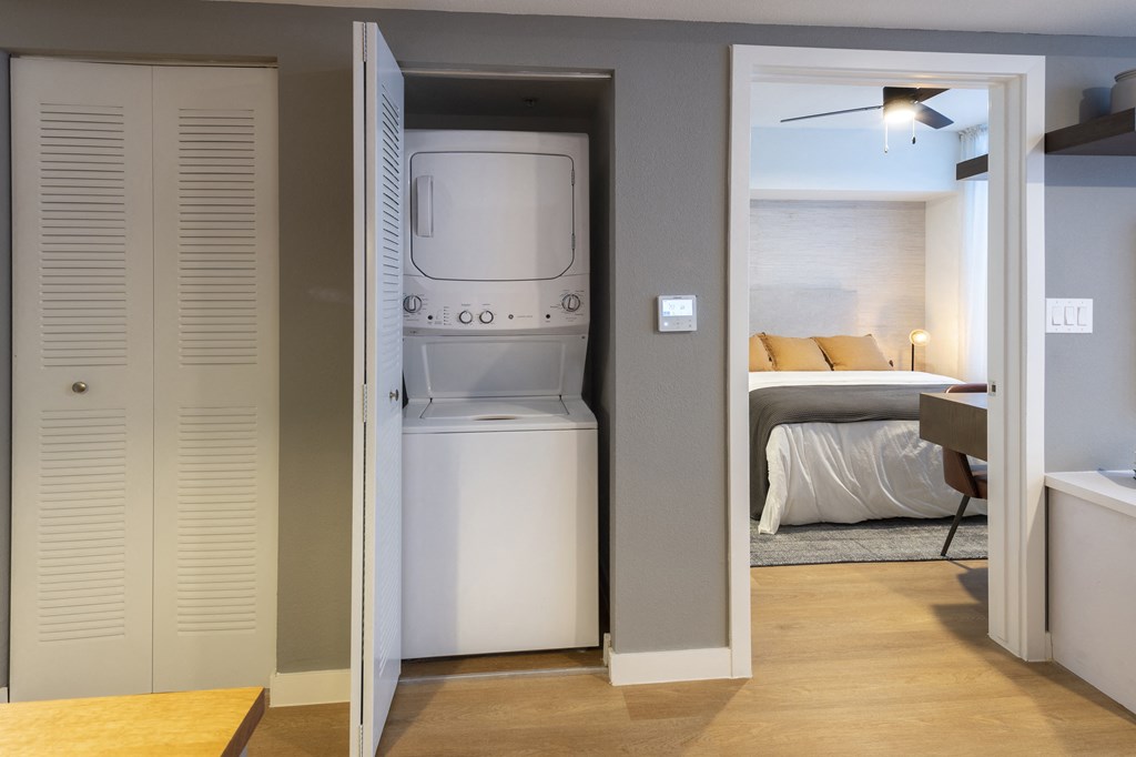 a room with a washer and dryer in a closet next to a bedroom