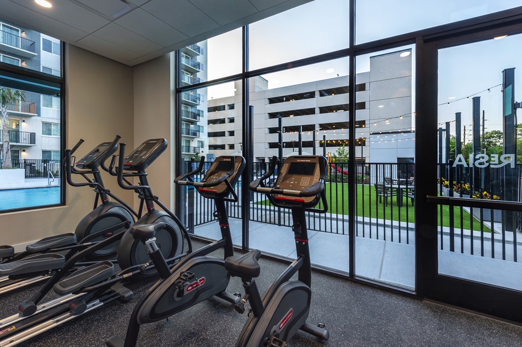 cardio bikes in the gym of a building with a view of theenced in patio
