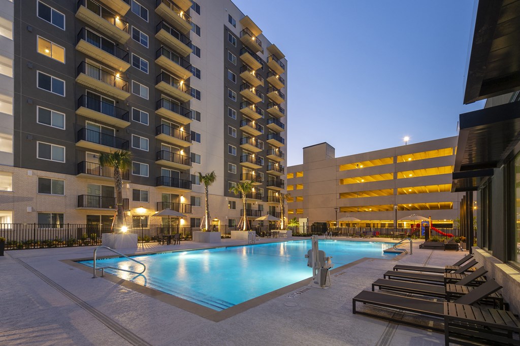 a swimming pool in front of an apartment building at night