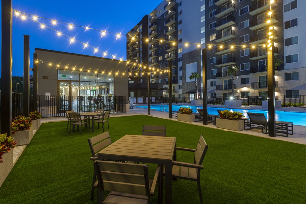 a rendering of a yard with tables and chairs and a pool at night