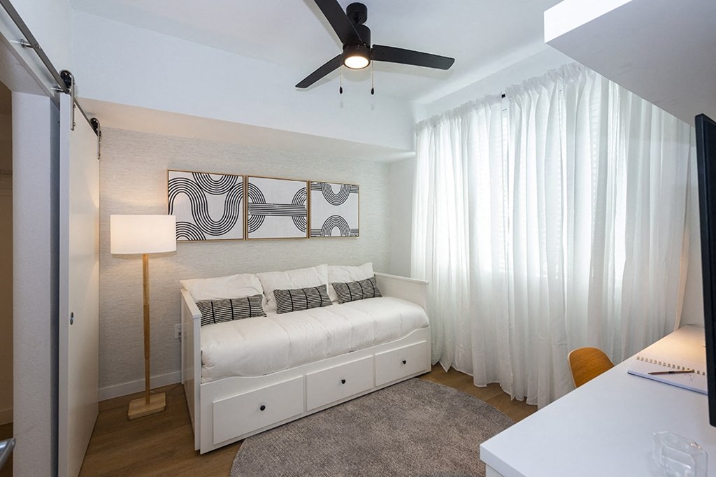 a bedroom with a white bed and a ceiling fan