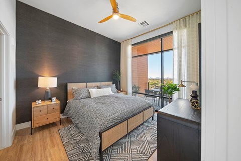 A bedroom with a bed, nightstand, and a ceiling fan.