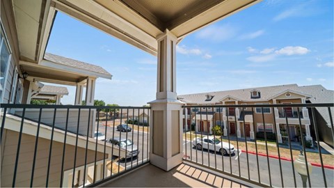 A balcony overlooks a parking lot and buildings.