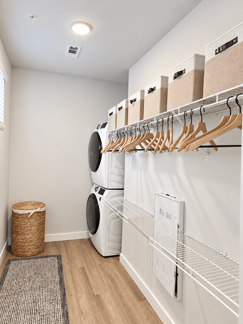 A laundry room with a washer and dryer and a rack of clothes.