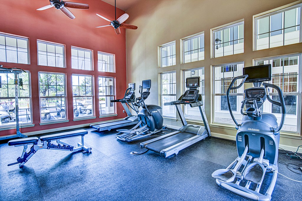 A gym with treadmills, elliptical machines, and a fan.