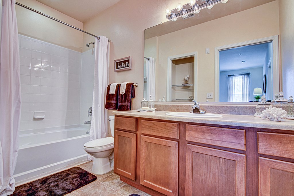 A bathroom with a wooden vanity and a white bathtub.