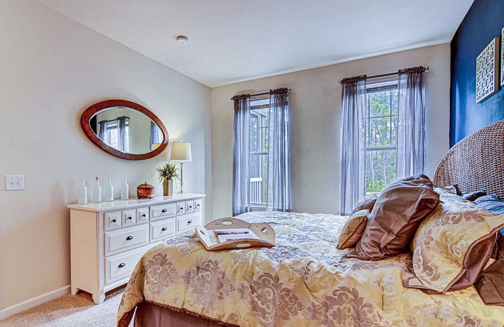 A bedroom with a bed, dresser, and mirror.