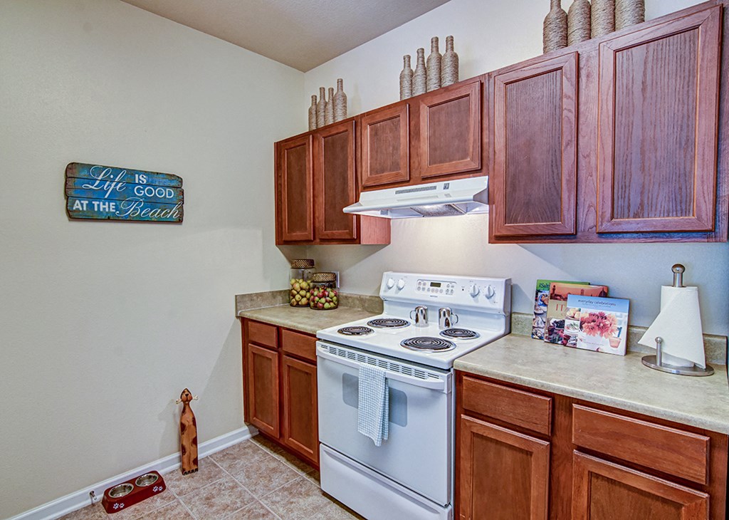 A kitchen with a white stove and wooden cabinets.