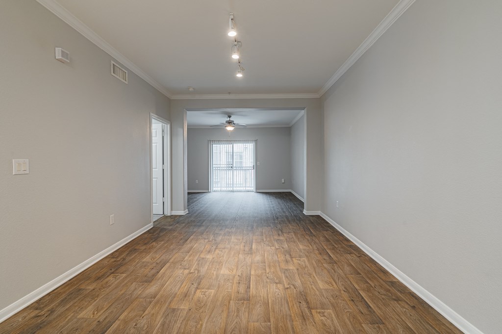 the living room and dining room of an empty house with wood flooring