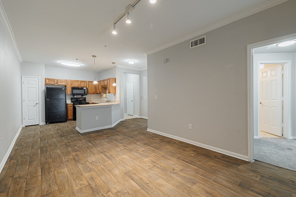 an empty living room and kitchen with wood flooring