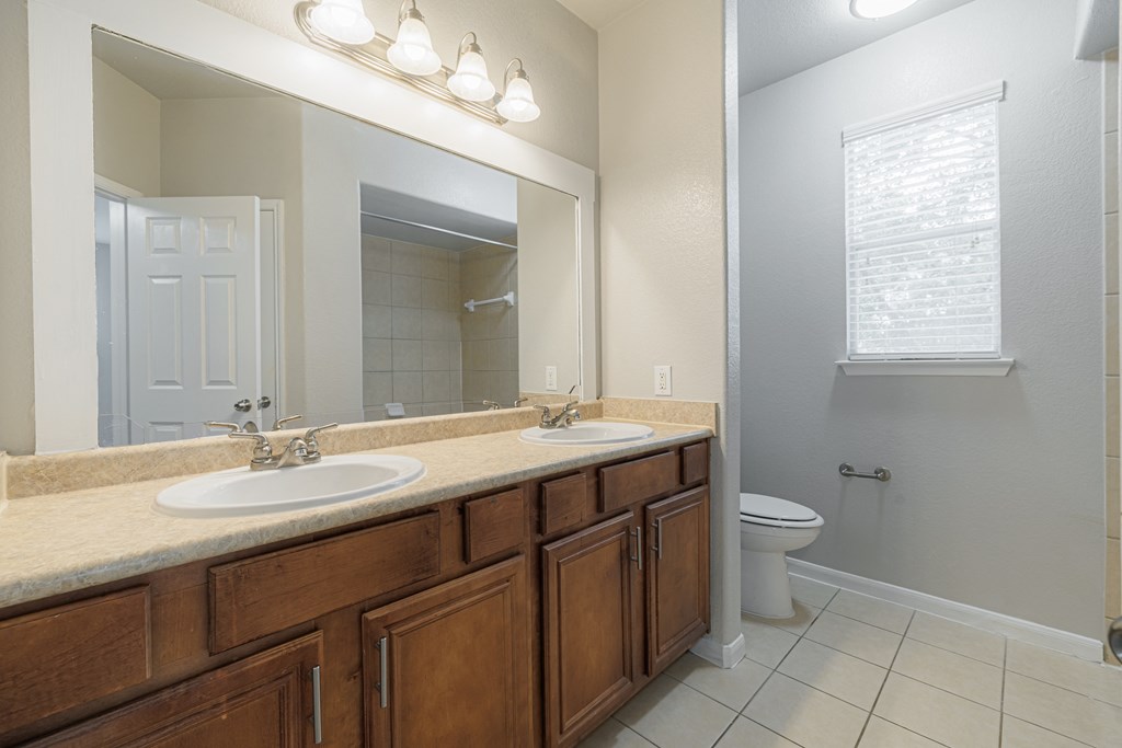 an empty bathroom with two sinks and a toilet
