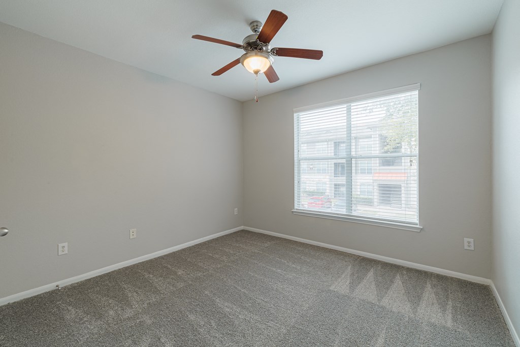 an empty room with a ceiling fan and a window