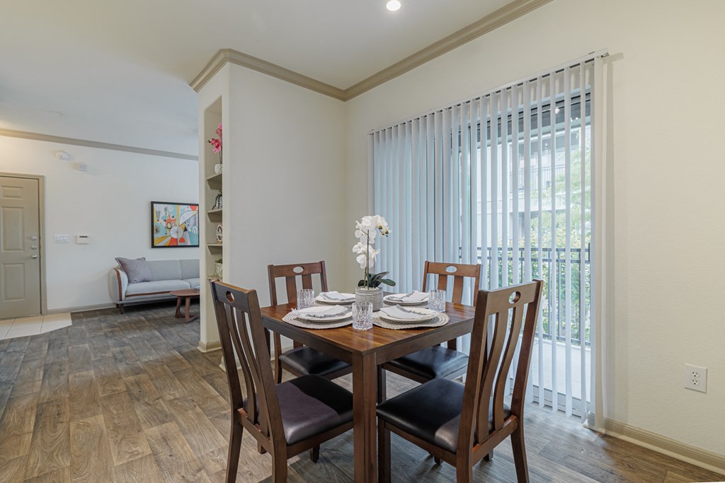 a dining room with a wooden table and chairs and a large window