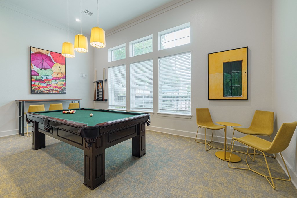 a games room with a pool table and chairs